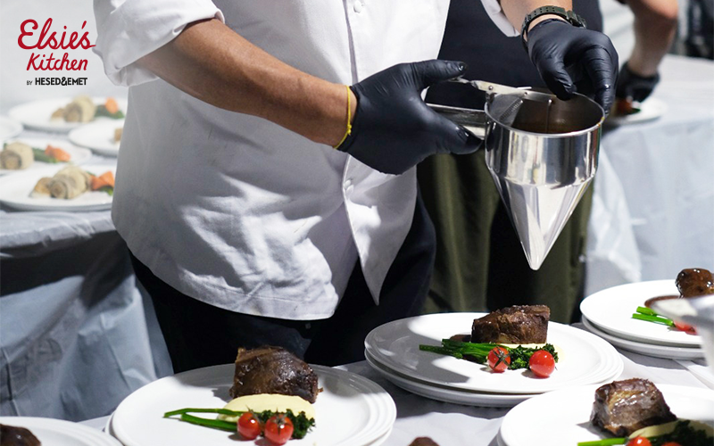 Wedding catering as a chef plates gourmet food, elegantly presented with fine silverware.